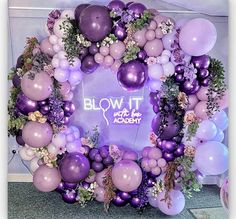 a purple and white balloon arch with flowers on it that says blow it with the academy