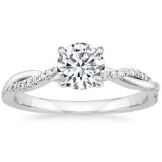 a white gold engagement ring with diamonds on the band and a round cut diamond in the center