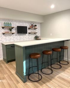 a kitchen with three bar stools and a television mounted on the wall above it