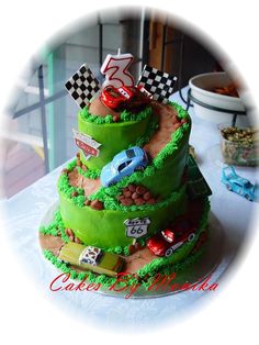 a three tiered cake decorated with cars and race flags on the top is shown