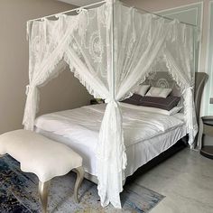 a canopy bed with white curtains and pillows