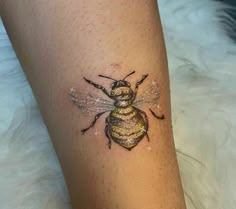 a small bee tattoo on the leg