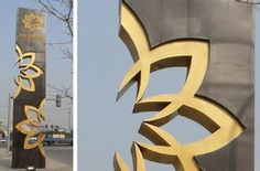 there are two large metal sculptures on the side of the road, one is gold and the other is black