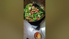 a pan filled with salad sitting on top of a stove next to an empty bowl