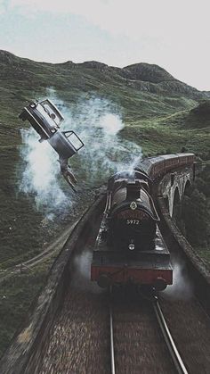 a train traveling down tracks next to a lush green hillside