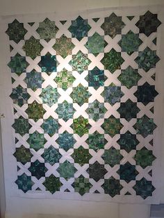 a wall hanging made out of green and white tiles