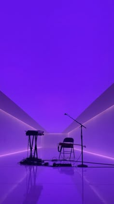 an empty room with two chairs and microphones in the middle, purple lighting on the ceiling