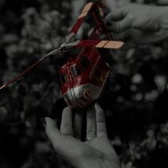 two hands holding a toy helicopter in the air