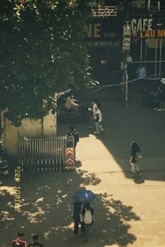 people walking down the sidewalk with umbrellas on a sunny day