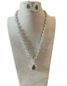 Elevate your style with our Emerald Green Silver Diamond Necklace Set, featuring high-quality CZ diamonds and matching studs. This exquisite set is perfect for engagement parties, cocktail events, and weddings, adding a touch of elegance to any occasion. The rich emerald green stones complement the sparkling silver diamonds, creating a captivating ensemble that matches effortlessly with your wardrobe. Embrace sophistication and glamour with this stunning jewelry set, designed to enhance your special moments.  All our products are crafted using traditional skills from our rich heritage. The manual nature of these crafts means that irregularities or variations may inherent in the handcrafting process. Green Diamond Necklace, Diamond Necklace Indian, Emerald Green Stone, Silver Diamond Necklace, Engagement Parties, Cocktail Set, Diamond Necklace Set, Green Stones, Bollywood Jewelry