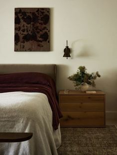 a bedroom with a bed, nightstand and painting on the wall