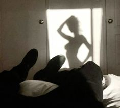 a person laying in bed with their shadow on the wall