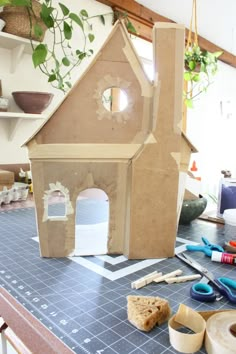 a house made out of cardboard sitting on top of a table next to craft supplies