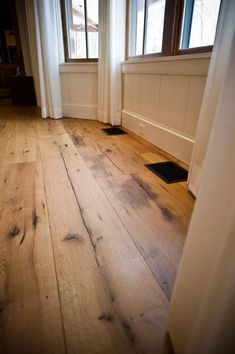 an empty room with wooden floors and windows