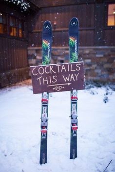 two skis are propped up in front of a sign that says cocktails this way