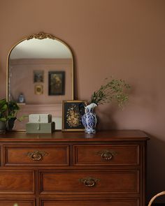 a dresser with a mirror and vase on top