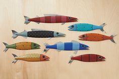 five fish made out of wood sitting on top of a wooden table