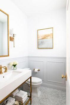 a bathroom with white walls and gold accents