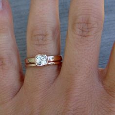 a woman's hand with two gold rings on it and a diamond ring in the middle