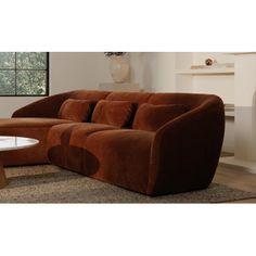 a brown couch sitting on top of a rug next to a table