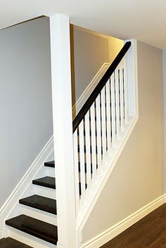 a white staircase with black handrails and wood flooring