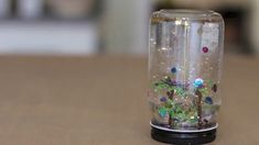 a glass vase with plants inside sitting on a table