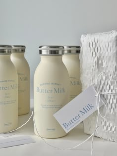 three jars with labels on them are sitting next to a basket and some twine