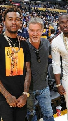 three men standing next to each other in front of a crowd at a basketball game