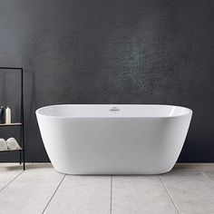 a white bath tub sitting on top of a tiled floor next to a black wall