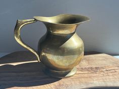 a brass pitcher sitting on top of a wooden table