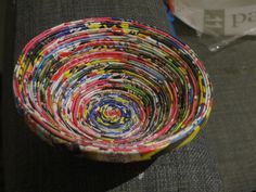 a multicolored bowl sitting on top of a couch next to a plastic bag