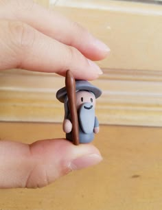 a hand holding a small figurine in the shape of a man with a hat and cane