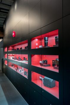 an apple store with red lighting on the wall and black shelves filled with electronic equipment