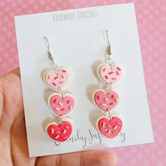 a pair of pink and white heart shaped earrings