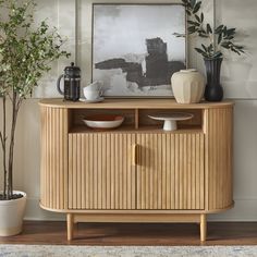 a wooden cabinet sitting next to a potted plant