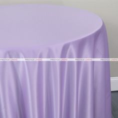 a round table covered with a purple satin tablecloth and white wall in the background