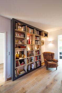 a living room filled with lots of furniture and bookshelves next to a doorway