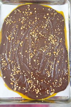 a cake with chocolate frosting and sprinkles in a glass dish on a table