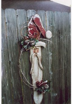 a piece of wood that has been decorated with christmas decorations on it and is leaning against a wooden fence