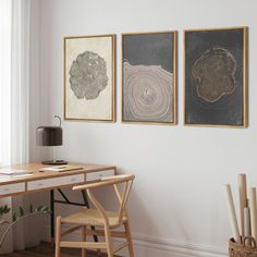 three paintings hang on the wall above a desk