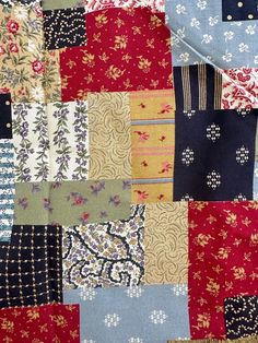 an old patchwork quilt with many different colors and patterns on the fabric, as well as flowers