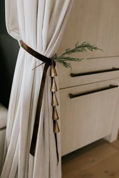 the curtains are pulled back and tied together with brown ribbon on them, along with some green plants