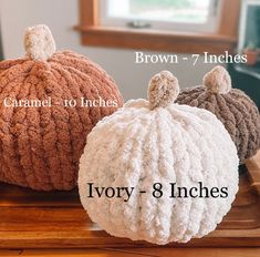 three crocheted pumpkins sitting on top of a wooden table