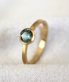 A dainty ring sits on some cream coloured linen and features a mint green bi-colour bezel-set sapphire ring in 18 carat yellow gold. Handmade Elegant Green Moonstone Ring, Platinum Green Gemstone Rings, Minimalist Green Crystal Gemstone Ring, Minimalist Green Gemstone Ring, Green Gemstone Ring Gold-plated