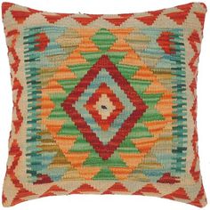 an orange and green pillow with multicolored diamonds on the front, sitting on a white background