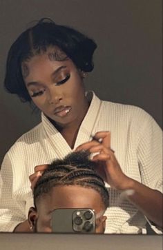 a woman is getting her hair styled by another person in front of a mirror with an electronic camera