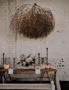 a table with candles and flowers on it in front of a white brick wall that says willow and bear following