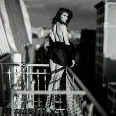 a black and white photo of a woman in a dress on top of a building