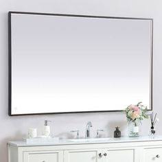 a bathroom vanity with a large mirror above it and flowers in vases on the counter