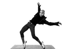 a black and white photo of a man jumping in the air with his arms outstretched